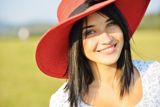 Hermosa chica con sombrero rojo en Prado de verano