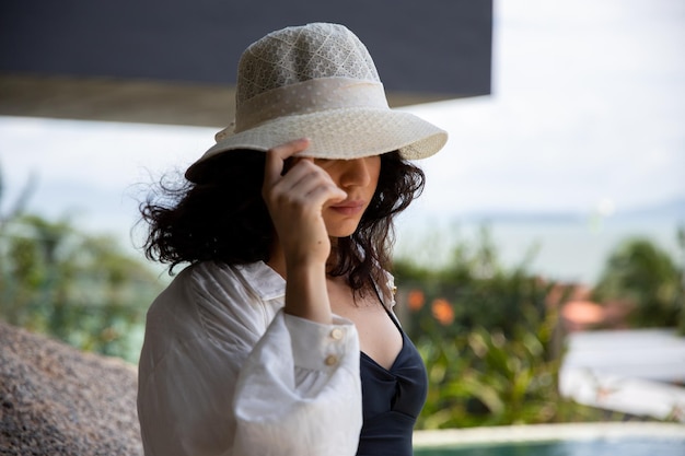 Hermosa chica con un sombrero rojo sonriendo a la orilla del verano