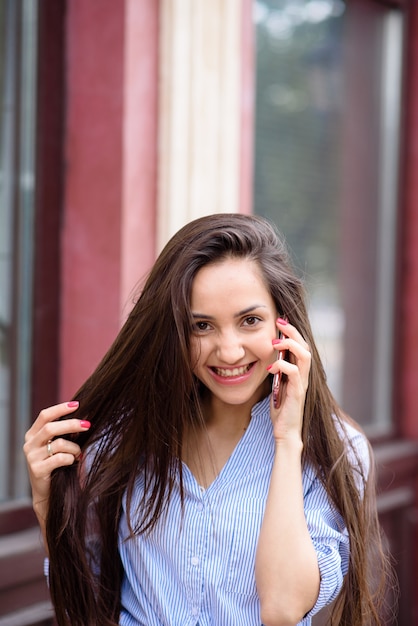 Hermosa chica sonriendo y hablando por teléfono.