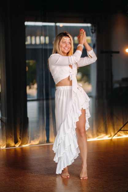 Hermosa chica sonriente con un vestido blanco bailando en el gimnasio