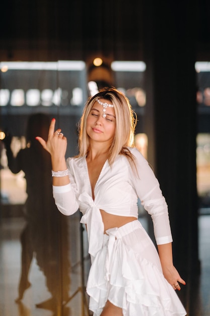 Hermosa chica sonriente con un vestido blanco bailando en el gimnasio