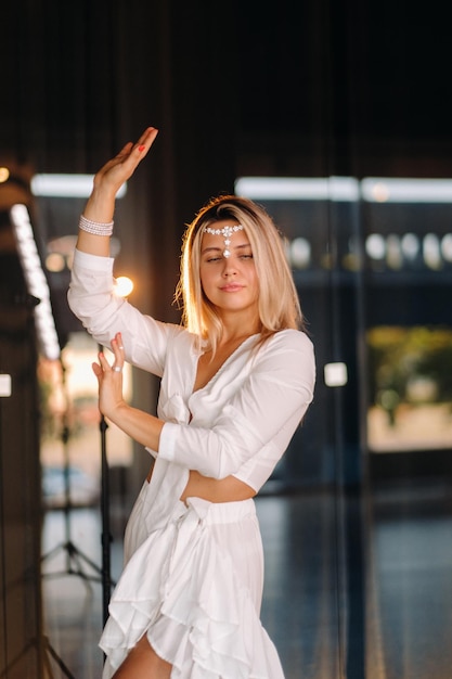 Hermosa chica sonriente con un vestido blanco bailando en el gimnasio