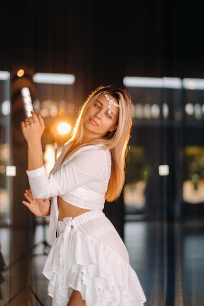 Hermosa chica sonriente con un vestido blanco bailando en el gimnasio