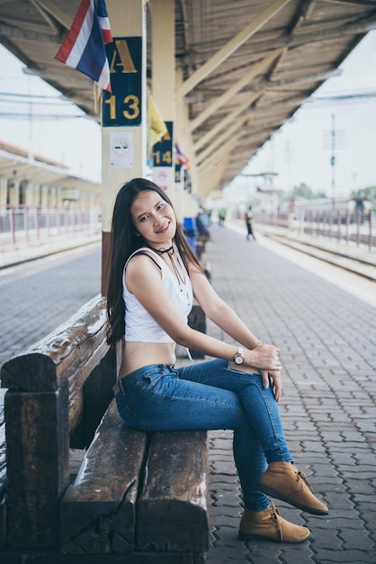 Hermosa chica con sonrisa espera el tren para ir a viajar a la estación de tren estilo vintage