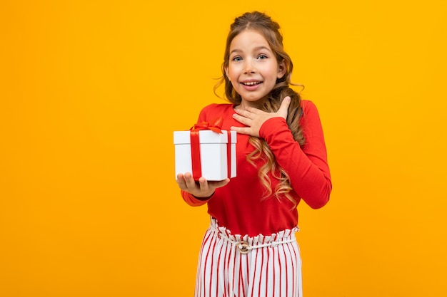 Hermosa chica sorprendida con una caja de regalo en amarillo con espacio de copia