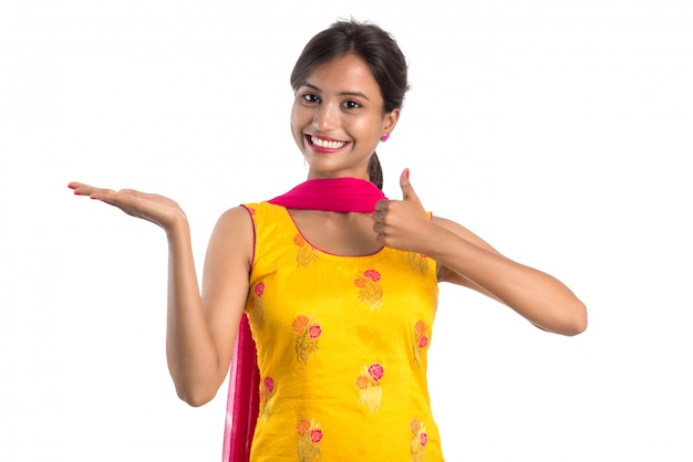 Hermosa chica sosteniendo y presentando algo en la mano con una sonrisa feliz.