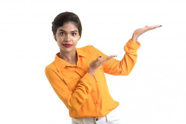 Hermosa chica sosteniendo y presentando algo en la mano con una sonrisa feliz.