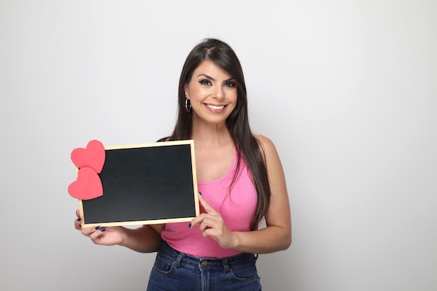 Hermosa chica sosteniendo el regalo de San Valentín sobre fondo blanco.