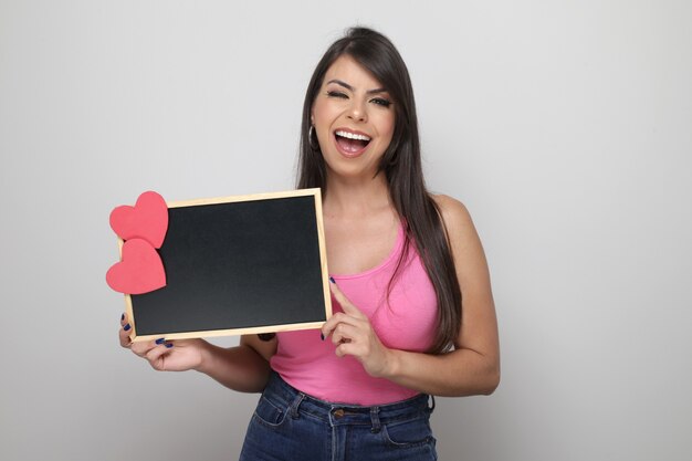 Hermosa chica sosteniendo el regalo de San Valentín sobre fondo blanco.