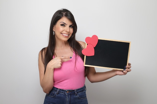 Hermosa chica sosteniendo el regalo de San Valentín sobre fondo blanco.