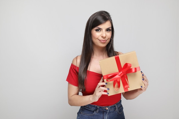 Hermosa chica sosteniendo el regalo de San Valentín sobre fondo blanco.