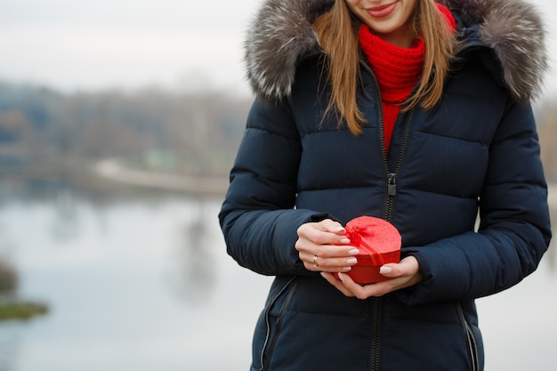 Hermosa chica sostiene una caja con un regalo en sus manos El concepto para el día de San Valentín