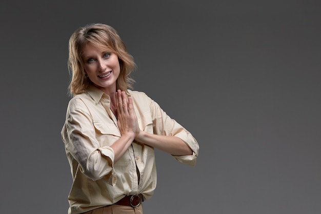 Hermosa chica sostiene que sus palmas están dobladas frente a su pecho para rezar sobre un fondo gris. Meditación. concepto de fe, espiritualidad y religión. Copiar spase