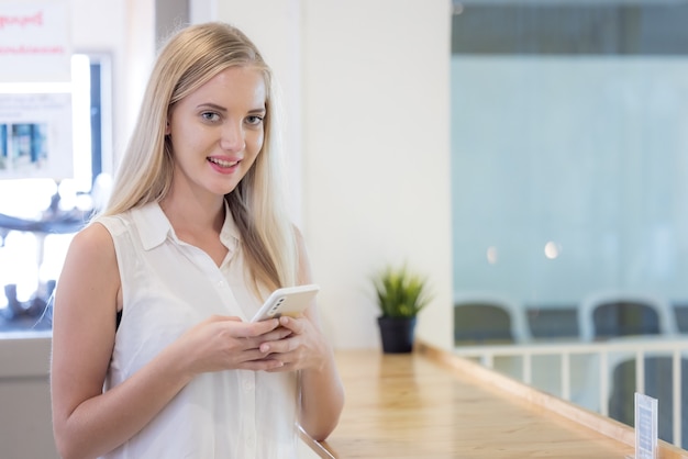 Hermosa chica con su teléfono móvil en una cafetería feliz y sonrisa.