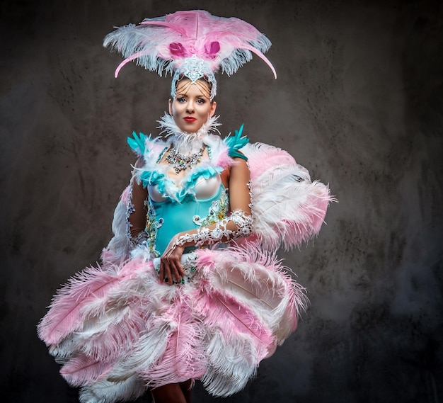 Hermosa chica en un suntuoso traje de plumas de carnaval. Aislado en un fondo oscuro.