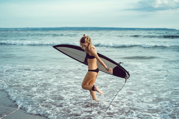 Hermosa chica en una tabla de surf en el océano