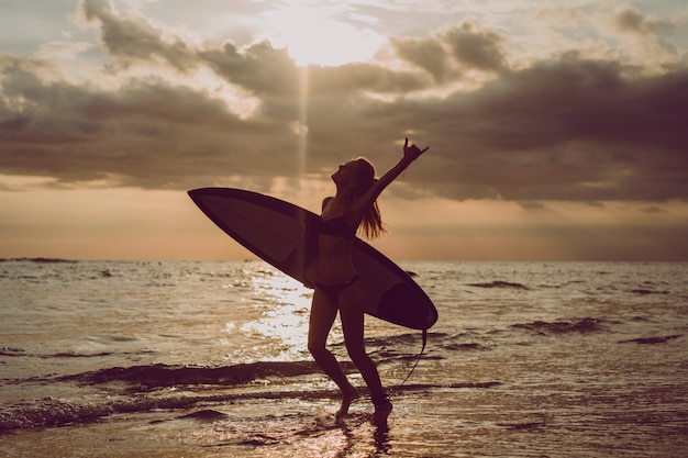 Hermosa chica en una tabla de surf en el océano