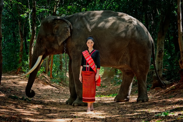 Hermosa chica tailandesa en traje tradicional. Mujer tailandesa en traje tradicional con elefante.