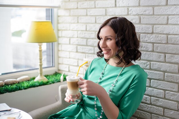 Hermosa chica con una taza de café con un vestido verde