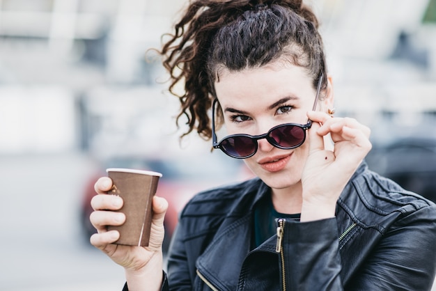 Hermosa chica toma café en la calle