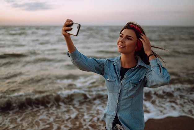 Hermosa chica se toma un selfie en la playa al atardecer El concepto de viajes relajantes y vacaciones de verano