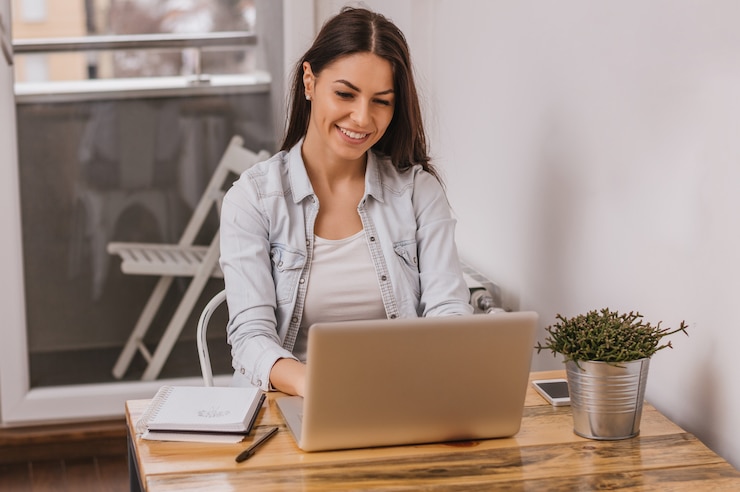 Foto hermosa chica trabajando en la computadora en casa