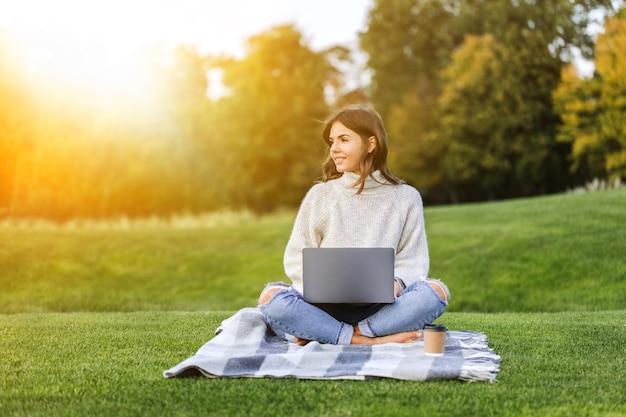 Hermosa chica trabajando en una laptop en el parque