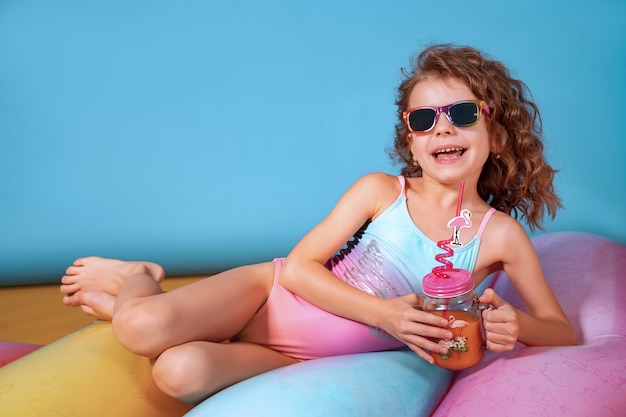 Hermosa chica en traje de baño colorido y gafas de sol con cóctel de piña