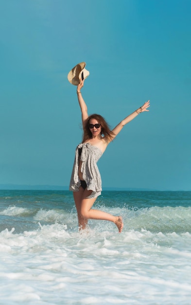 Una hermosa chica en traje de baño en verano en la orilla del mar felizmente divirtiéndose en el agua con emociones