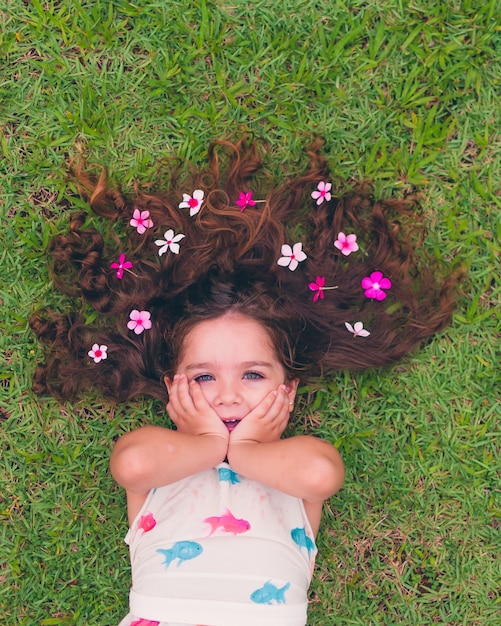 Hermosa chica tumbada en la hierba con flores en el pelo