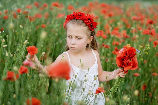 Hermosa chica ucraniana en campo de amapolas y trigo.