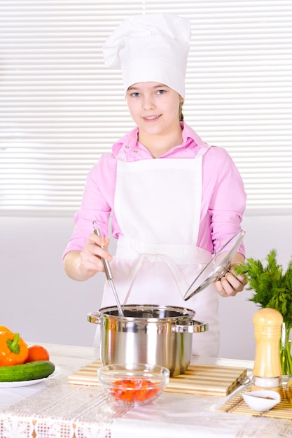 Hermosa chica con uniforme de chef cocinando