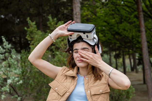 Hermosa chica usando un set de realidad virtual y frotándose los ojos