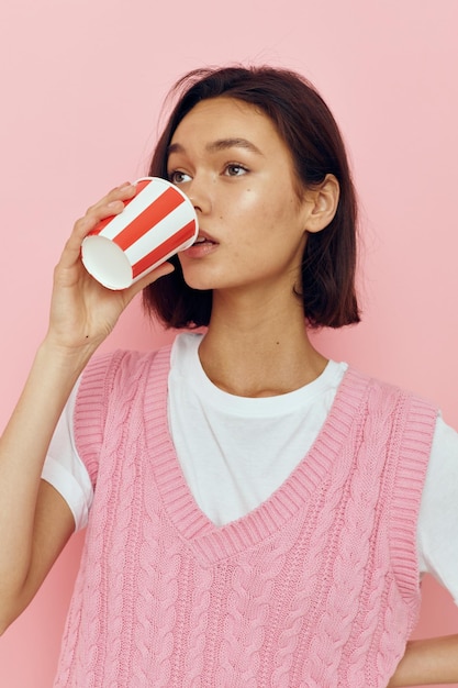 Hermosa chica vaso de bebida desechable en una camiseta rosa fondo aislado