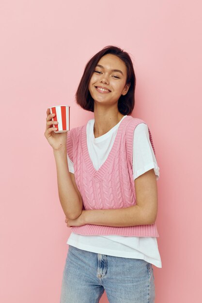 Hermosa chica vaso de bebida desechable en una camiseta rosa fondo aislado