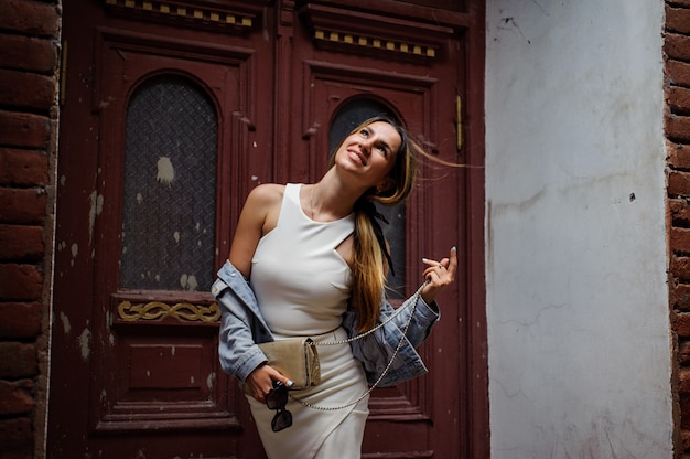 Foto hermosa chica en vestido ajustado posando delante de las puertas