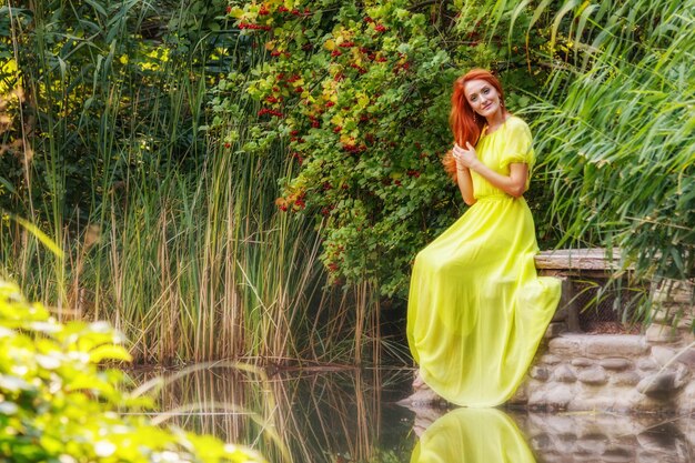 Hermosa chica con vestido amarillo en la orilla del río