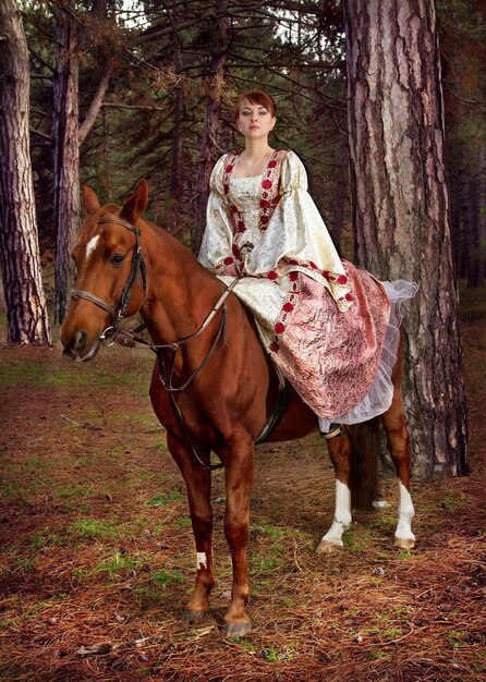 Hermosa chica en vestido antiguo a caballo