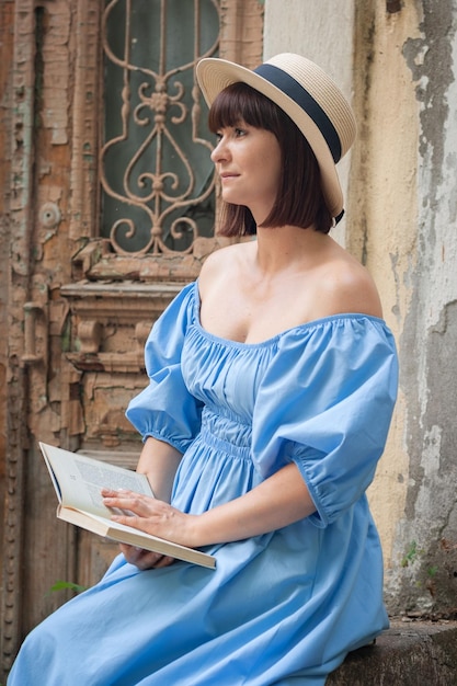 hermosa chica con un vestido azul con libros cerca de la puerta vieja