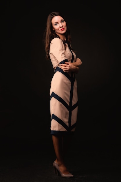 Hermosa chica con un vestido beige sobre un fondo oscuro