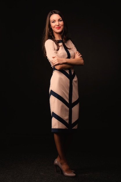 Hermosa chica con un vestido beige sobre un fondo oscuro