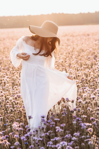 Hermosa chica con un vestido blanco en un campo de lavanda al atardecer