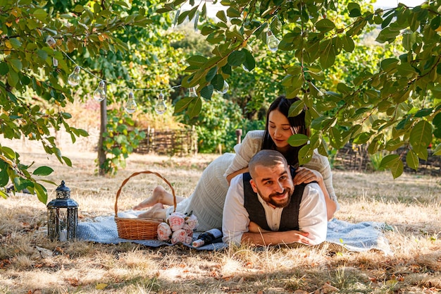 Hermosa chica con un vestido blanco y un chico yacen en un claro un picnic