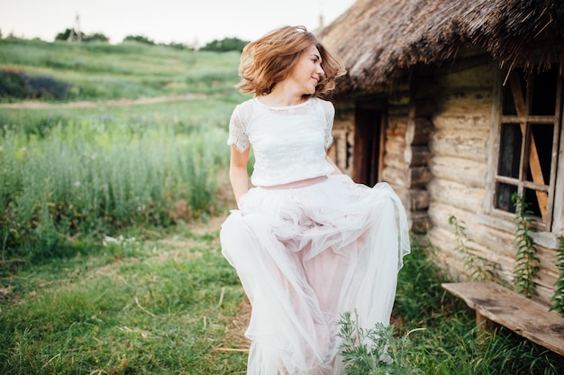 Hermosa chica en vestido blanco se encuentra en la hierba verde