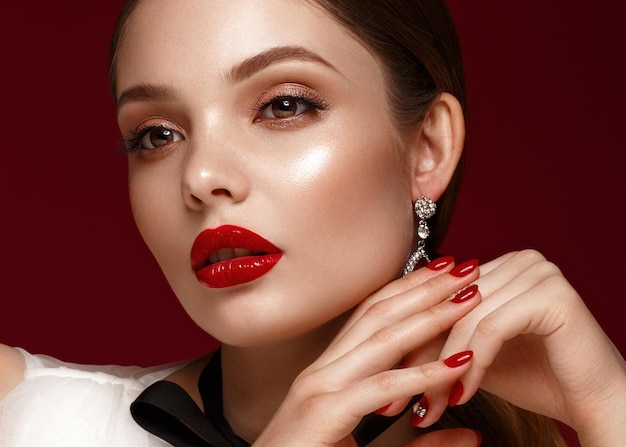 Hermosa chica con vestido blanco con maquillaje clásico y manicura roja Rostro de belleza Foto tomada en el estudio