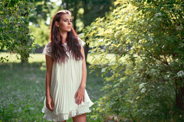 Hermosa chica con un vestido blanco en la naturaleza