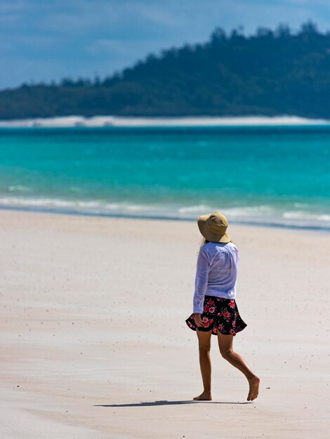 hermosa chica en vestido y camisa y sombrero camina en la playa de whitehaven, isla de whitsunday, australia