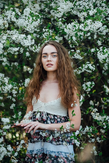 Una hermosa chica con un vestido se encuentra junto a un autobús de cerezas en flor