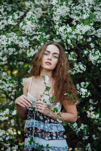 Una hermosa chica con un vestido se encuentra junto a un autobús de cerezas en flor