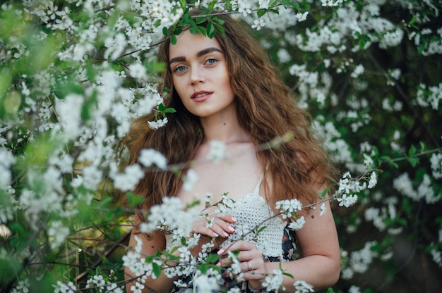 Una hermosa chica con un vestido se encuentra junto a un autobús de cerezas en flor